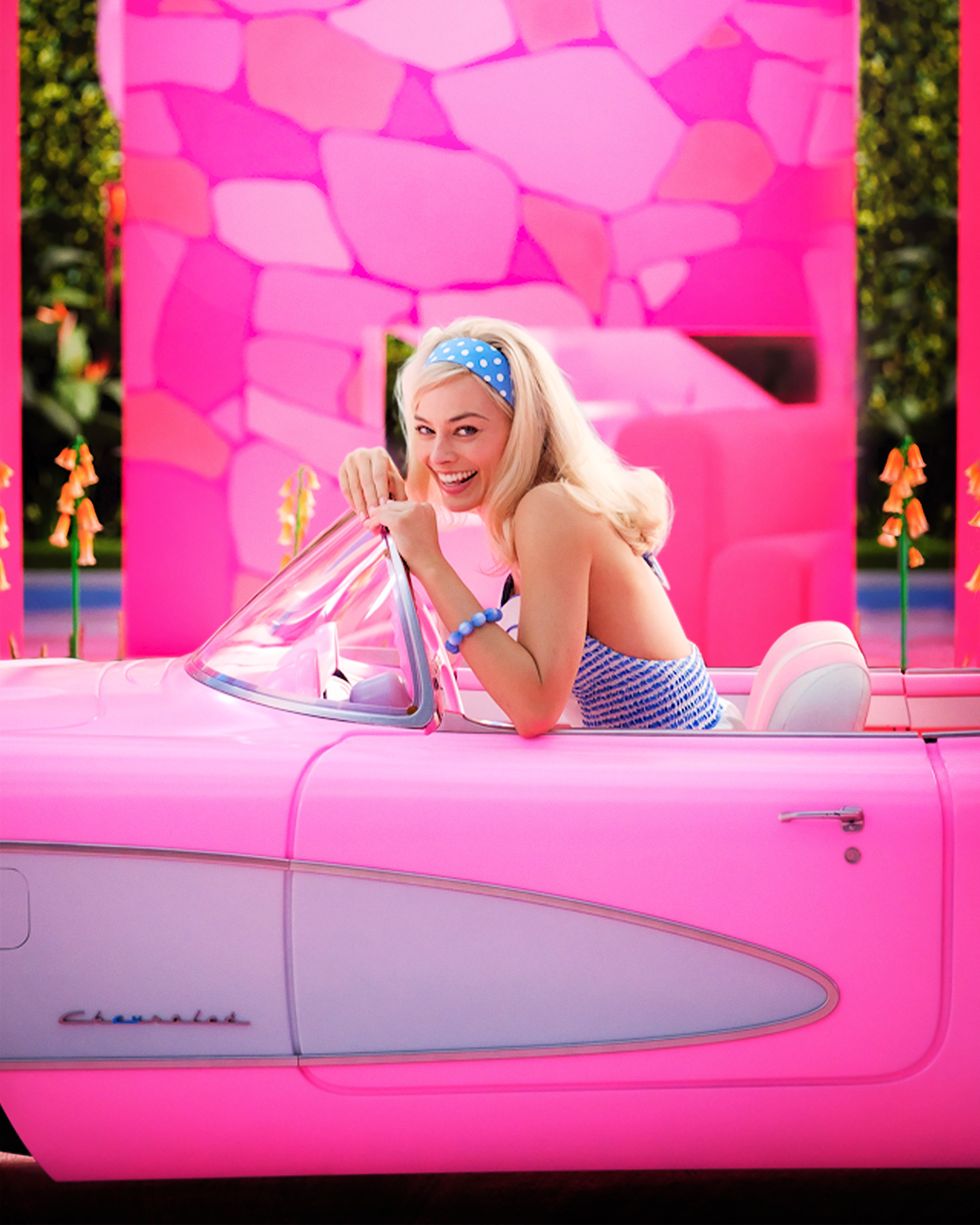 Smiling Barbie driving a pink car in a blue polka dot headband